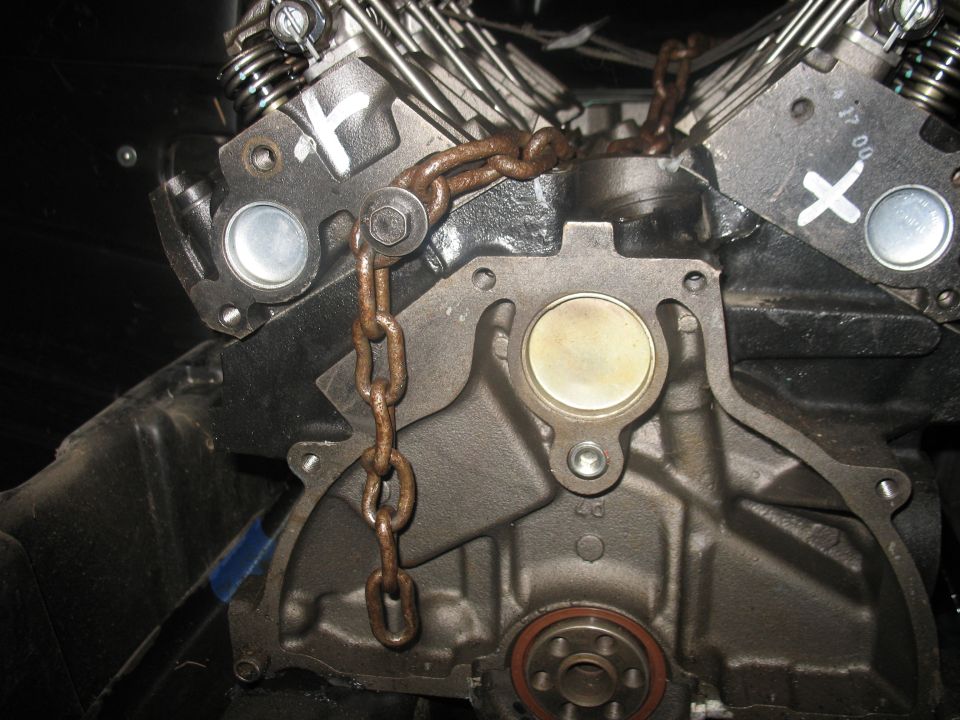 Engine block with a chain attached to the cylinder head. Some markings are visible on the head