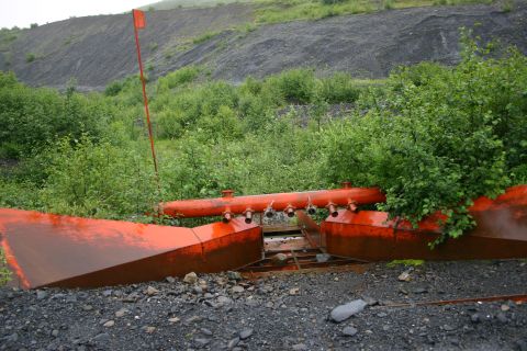 2003 Jeep TJ - Abandoned industrial equipment sits on a slag heap, partially covered by vegetation.