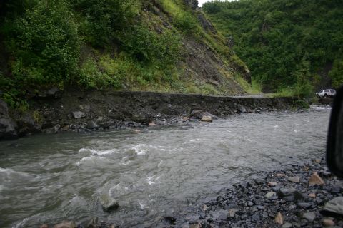2003 Jeep TJ - A white SUV drives on a road next to a river, where the road has partially collapsed.