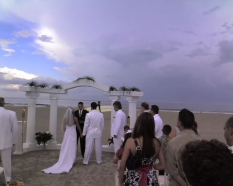 1989 Ford Bronco - A wedding ceremony takes place on a beach under a cloudy sky.