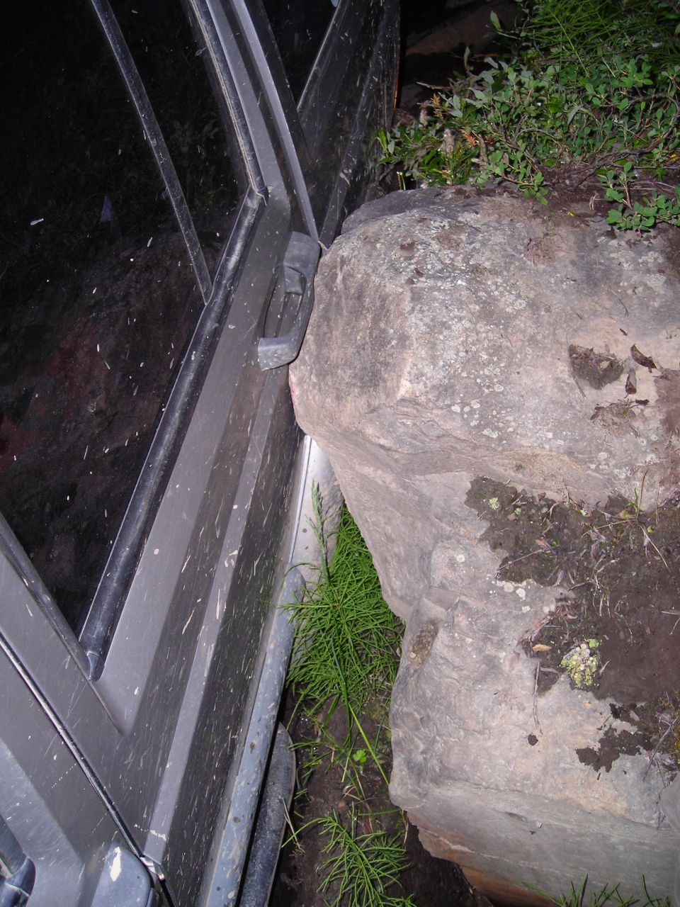 Jeep door wedged against a large rock on a trail