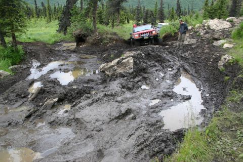 2003 Jeep TJ - Jeep Wrangler tackling a challenging muddy obstacle course on an off-road trail.
