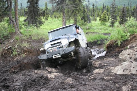 2003 Jeep TJ - This vintage Toyota Land Cruiser navigates a challenging off-road trail with mud and rocks.