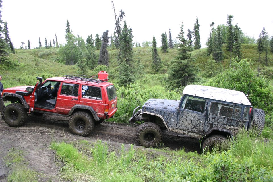 Red Jeep Cherokee and a muddy blue Jeep Wrangler off-roading