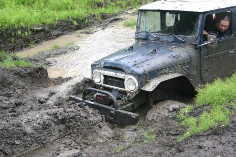 2003 Jeep TJ - This Toyota Land Cruiser FJ40 is deep in mud and water, struggling to get through.