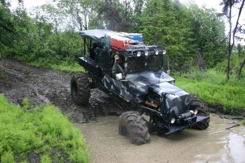 2003 Jeep TJ - A heavily modified off-road vehicle with a camouflage paint scheme tackles a challenging muddy terrain.