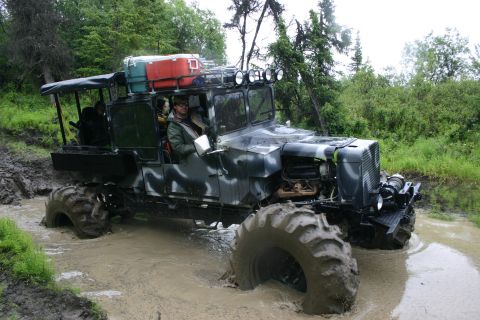2003 Jeep TJ - This heavily modified vehicle, equipped with oversized tires and a camouflage paint scheme, tackles a challenging muddy terrain.