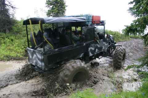 2003 Jeep TJ - Off-road vehicle navigates a muddy trail with passengers in the back.