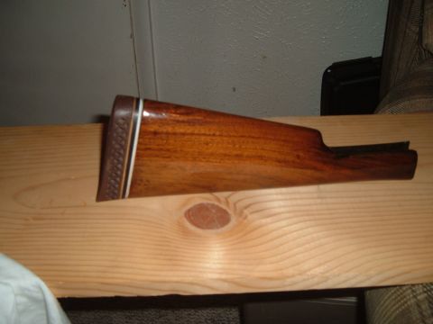1919 Yugo Vega - A close-up view of a wooden gun stock with a patterned butt plate and inlaid trim.