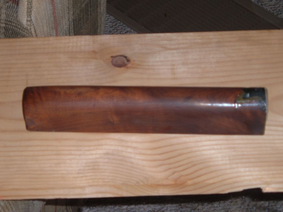 Polished wood rifle forend lying lengthwise on a pine board