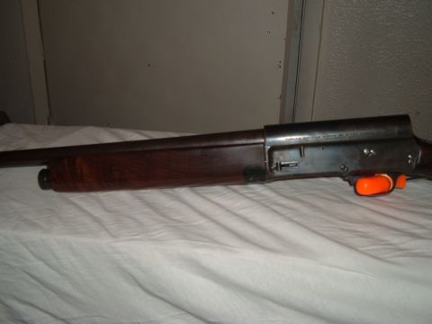 1919 Yugo Vega - A shotgun with a wooden stock and an orange trigger guard is shown in a side profile.