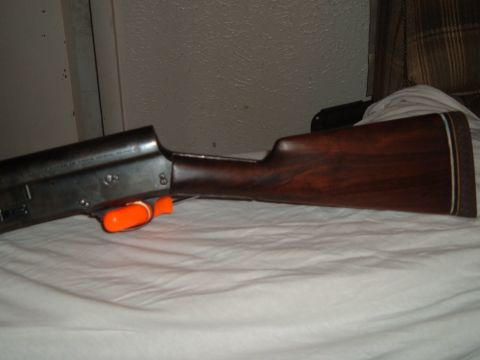 1919 Yugo Vega - Close-up of a shotgun's wooden stock and receiver, an orange safety mechanism.
