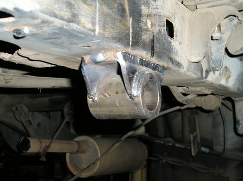 1986 Toyota Hilux - Close-up of a custom suspension mount welded onto a vehicle frame, with the exhaust system visible underneath.