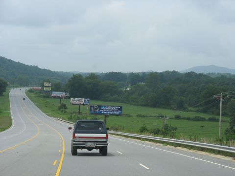 1995 Ford C-350 (Centurion Conversions) - Rear view of a 1995 Ford C-350 pickup truck on a highway with billboards in the background.
