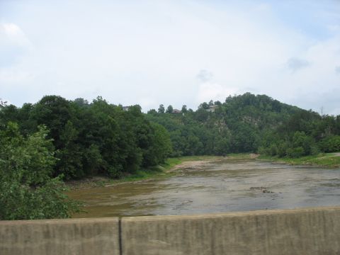 1995 Ford C-350 (Centurion Conversions) - A wide, shallow river winds through a valley with dense trees covering the hillsides.