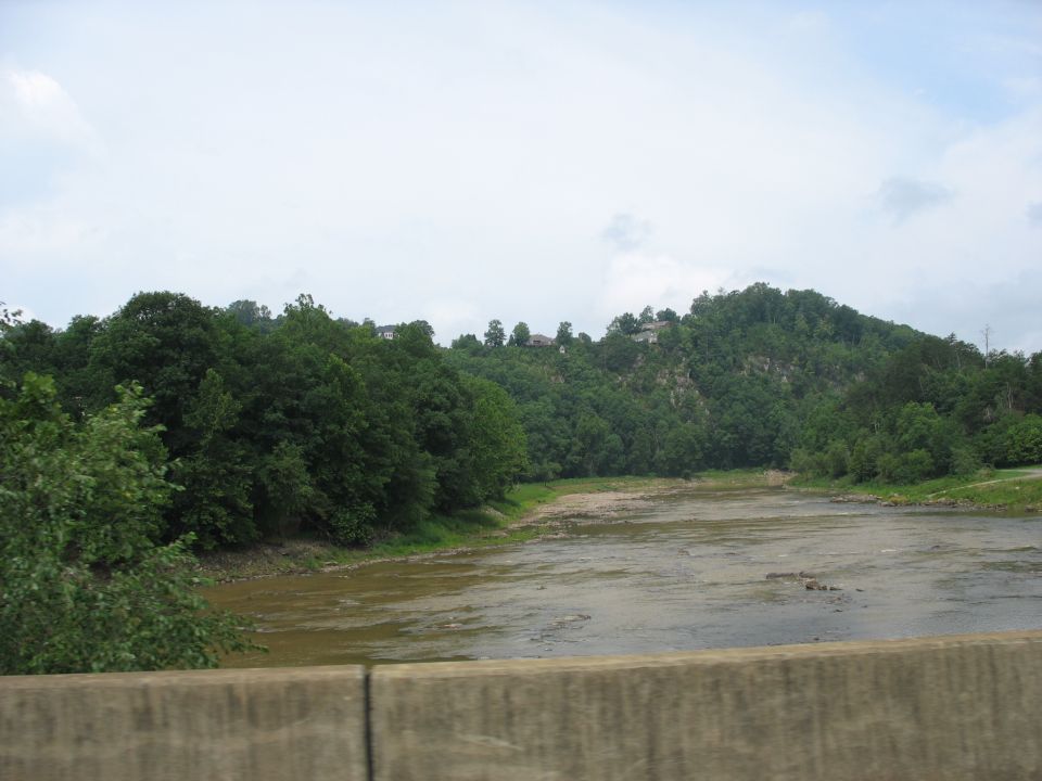 river flowing past wooded hills with houses on top