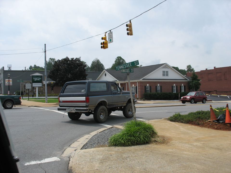 Gray lifted Ford Bronco from rear, with red SUV in background