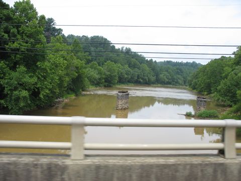 1995 Ford C-350 (Centurion Conversions) - View of a river and its surroundings from a bridge, with remnants of an old structure in the water.