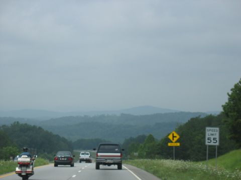 1995 Ford C-350 (Centurion Conversions) - A motorcycle and several cars travel down a highway, with a speed limit sign indicating 55 mph.