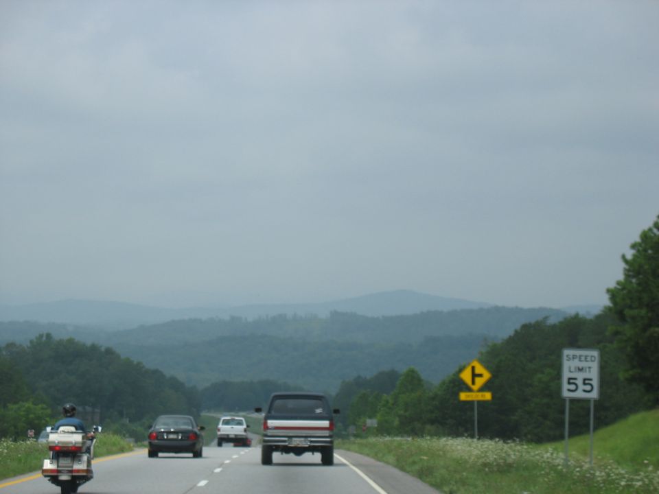 Motorcycle and cars on a highway with rolling hills in the background