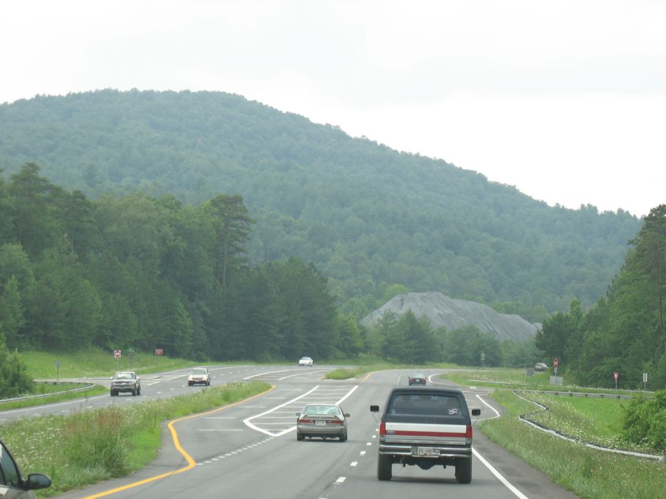 Pickup truck driving on a highway with a wooded mountain in the background