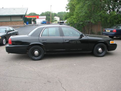 2000 Ford Crown Victoria - Side profile of a black 2000 Ford Crown Victoria, with another similar vehicle visible to the left.