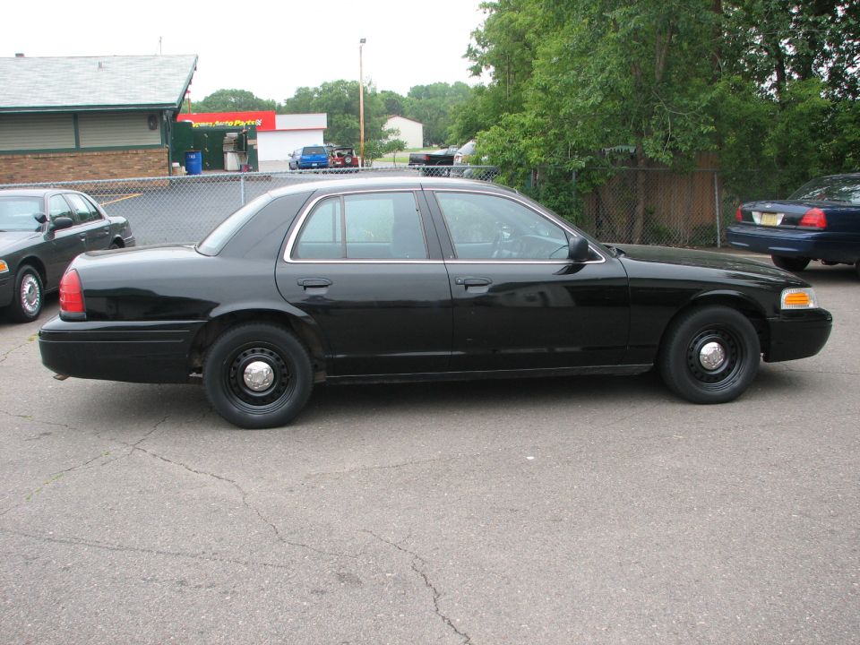 Black 2000 Ford Crown Victoria side view. Another Crown Victoria is parked to the left