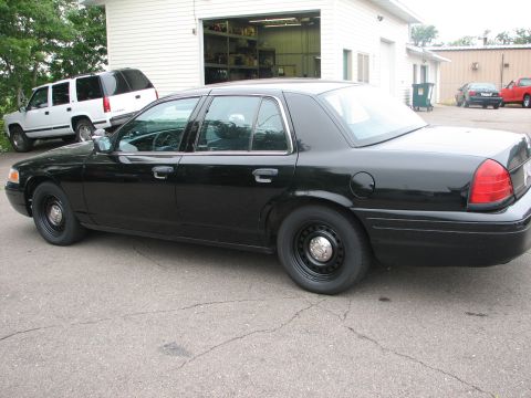 2000 Ford Crown Victoria - This black 2000 Ford Crown Victoria sedan is seen from the side, with another vehicle parked behind it.