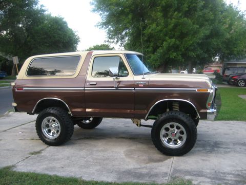1979 Ford Bronco - This lifted Ford Bronco is parked on a concrete driveway with trees in the background.