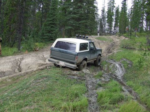 1990 Ford Bronco - A 1990 Ford Bronco navigates a challenging muddy track during an off-road event.