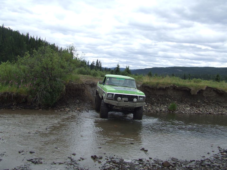 Green 1979 Ford F-Series pickup truck crossing a stream