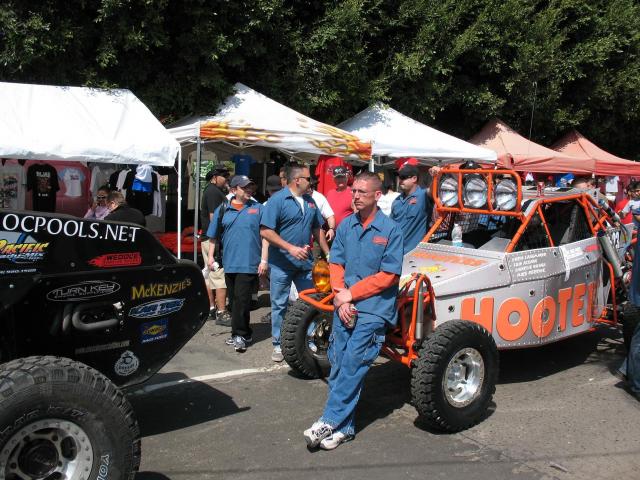Tube-frame off-road race buggies and crowd at an outdoor event