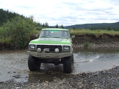 1990 Ford Bronco - This modified Ford Bronco is crossing a shallow stream in a natural landscape.
