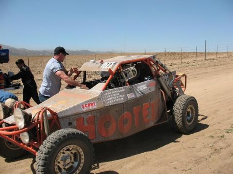 1992 Ford Bronco - A SCORE buggy with crew members attending to it in a desert-like environment under a clear blue sky.