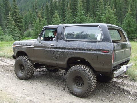 1990 Ford Bronco - This lifted 1978 Ford Bronco navigates a muddy trail surrounded by a dense forest.