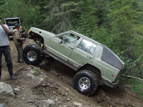 1990 Ford Bronco - A modified Jeep Cherokee XJ tackles a challenging off-road obstacle during a rally event.