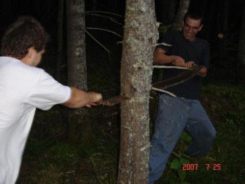 1990 Ford Bronco - Two men are shown in a wooded area at night, using machetes to cut down a tree.