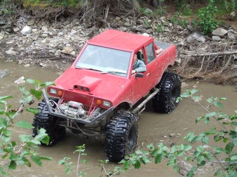 1990 Ford Bronco - This heavily modified off-road vehicle tackles a rocky stream bed during an outdoor rally event.