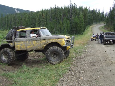 1990 Ford Bronco - A heavily modified 1967 Ford F-Series truck, likely a custom build, navigates a dirt road during an off-road event.