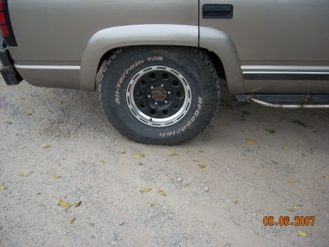 2000 Chevrolet Tahoe - A close-up view of the rear wheel and fender of a truck, showing aftermarket wheels and tires.