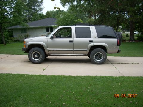 2000 Chevrolet Tahoe - Side view of a silver SUV, likely a Chevrolet Tahoe from the late 1990s, parked on a driveway.