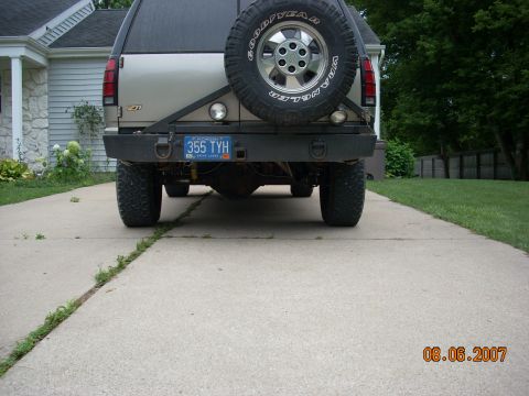 2000 Chevrolet Tahoe - The rear of an SUV is shown parked on a driveway, a spare tire and a custom bumper.