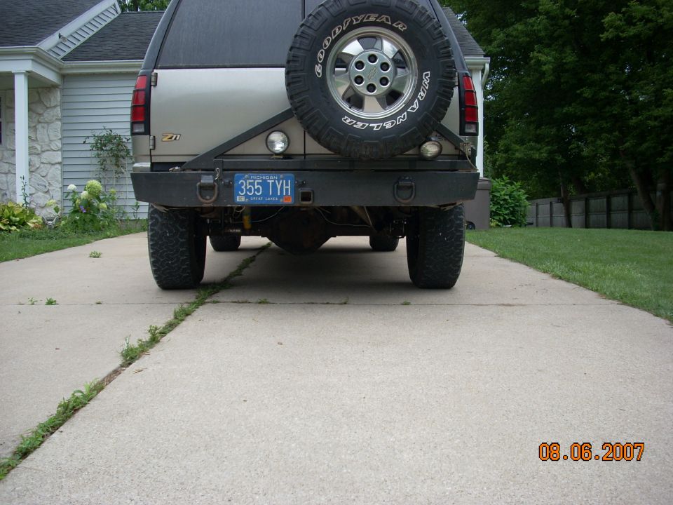 Rear view of an SUV with a spare tire mounted on the back, custom bumper, and a license plate