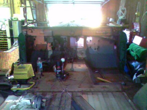 1974 Ford Bronco - Vehicle chassis undergoing work inside a cluttered garage space.