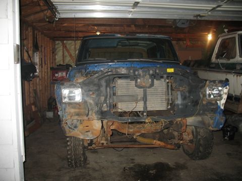 1978 Ford Bronco - This truck is missing its front end components and is parked in a garage with another vehicle.