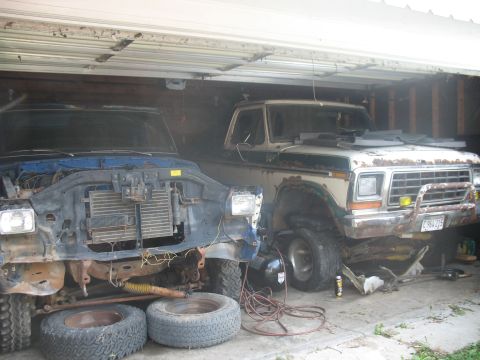 1978 Ford Bronco - Two Ford trucks are parked in a garage, one is partially disassembled.