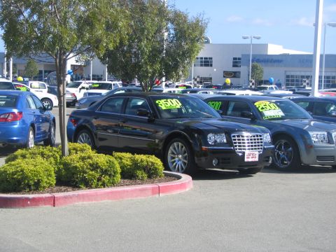 1975 Dodge Dart - A black Chrysler 300 sedan is displayed for sale at a dealership, with other vehicles visible in the background.