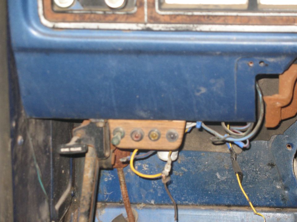 Close-up of dashboard wiring and aftermarket switches mounted on a wooden block