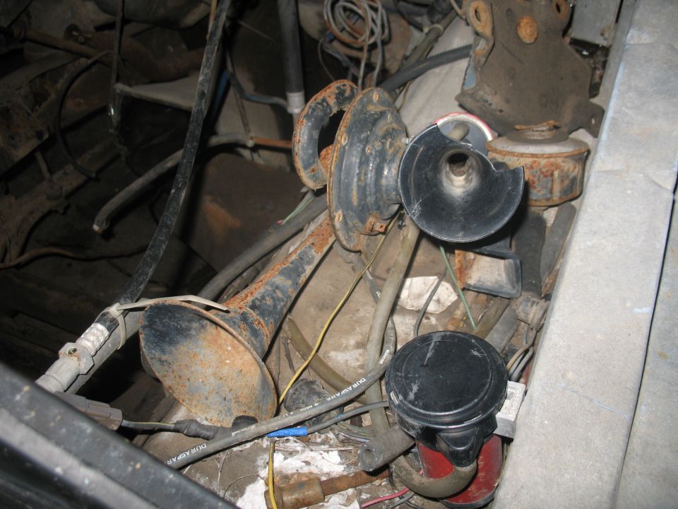 Engine bay showing rusty horns and tangled wiring