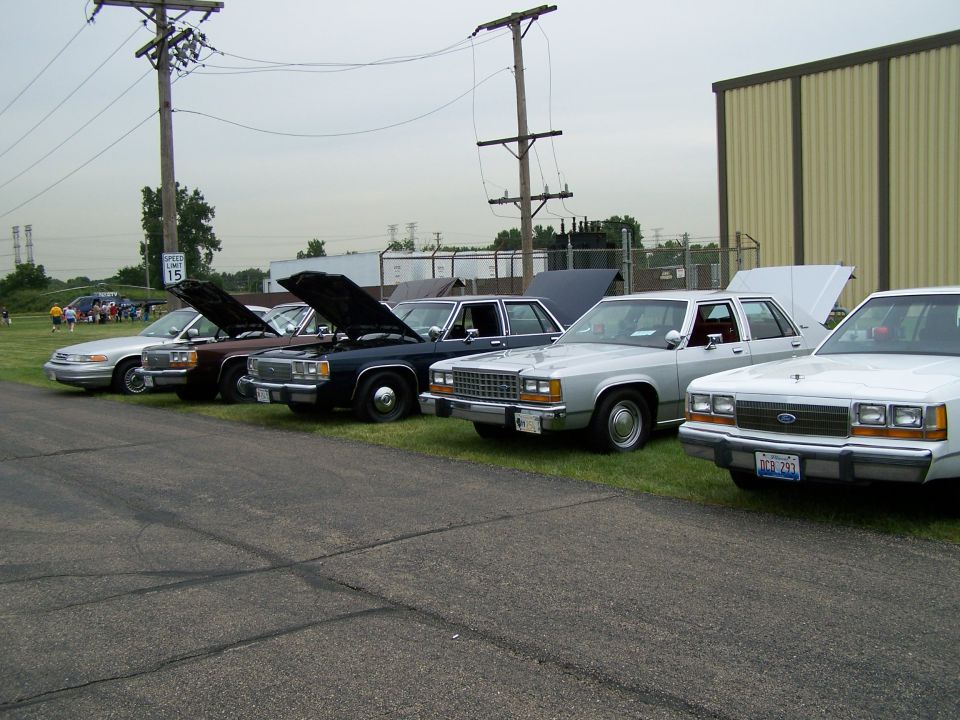 Silver sedan front view, hood open, parked in a line with other sedans